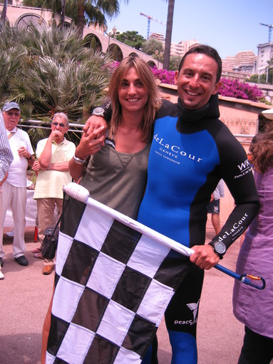 Il campione del mondo Pierre Frolla con la sua fidanzata e la bandiera del 69° GP di Monte-Carlo recuperata a 60 metri di profondità Il campione del mondo Pierre Frolla con la sua fidanzata e la bandiera del 69° GP di Monte-Carlo recuperata a 60 metri di profondità