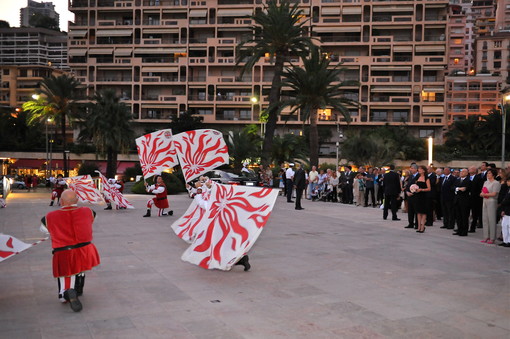 Lo spettacolo degli sbandieratori e sullo sfondo a destra: S.A.R. la Principessa Carolina, l'Ambasciatore Morabito e le autorità Lo spettacolo degli sbandieratori e sullo sfondo a destra: S.A.R. la Principessa Carolina, l'Ambasciatore Morabito e le autorità